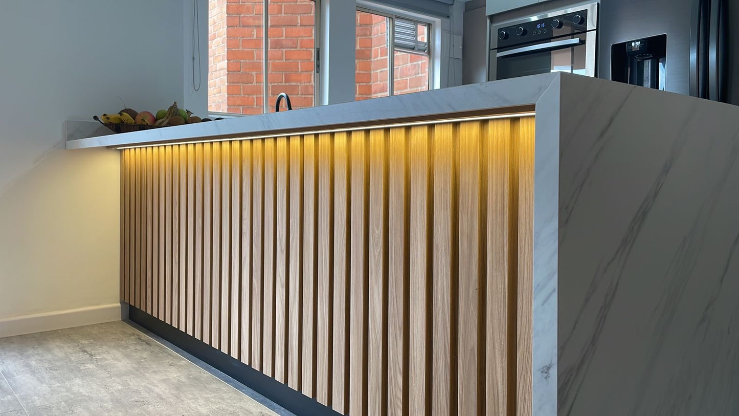 Cocina en madera ecológica en colores fresno europeo y taupe, con una isla que luce un impresionante mesón sinterizado Panda Grey